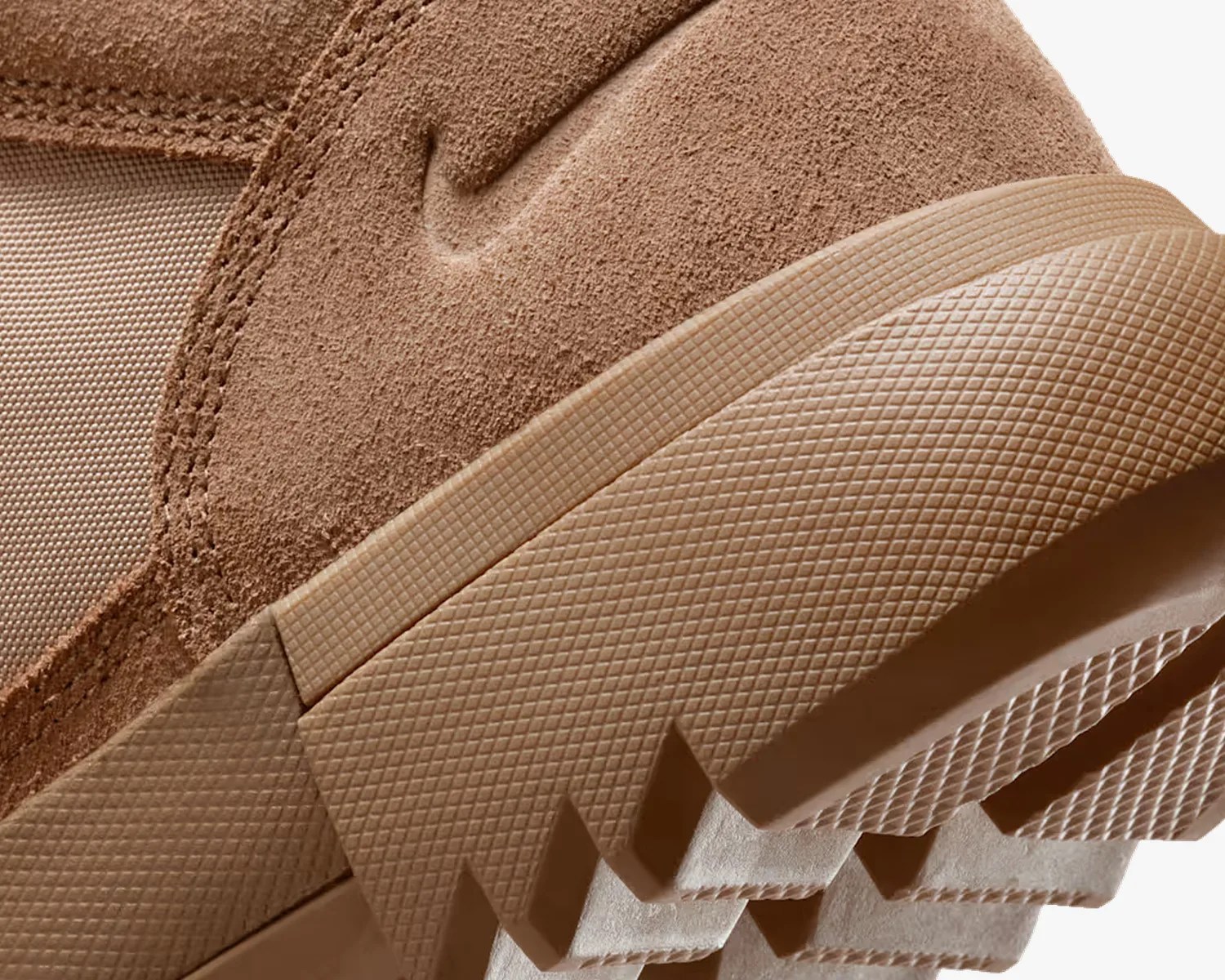 Close-up of a tan suede sneaker heel with textured rubber sole and stitched fabric panel.