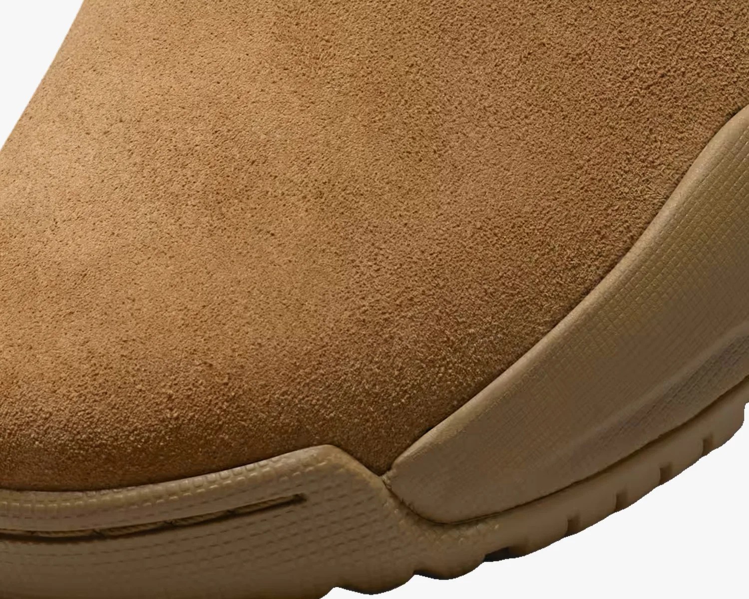 Close-up of a tan suede shoe toe with a textured rubber sole.