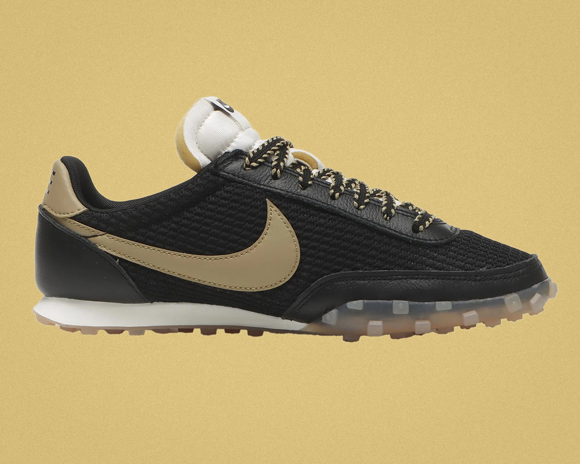 Black and beige Nike sneaker with mesh and leather upper, patterned laces, and translucent sole.
