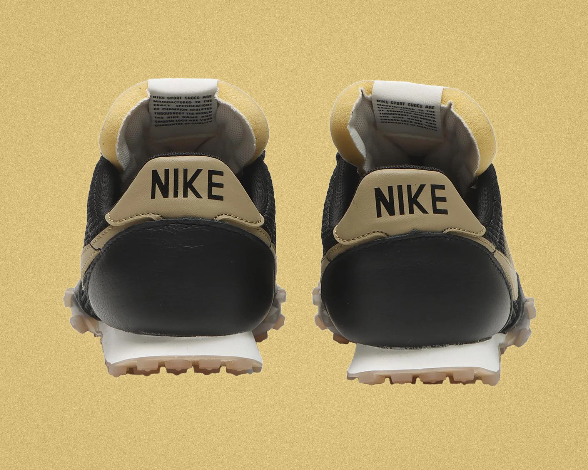 Pair of black and beige Nike sneakers viewed from the back on a beige background.