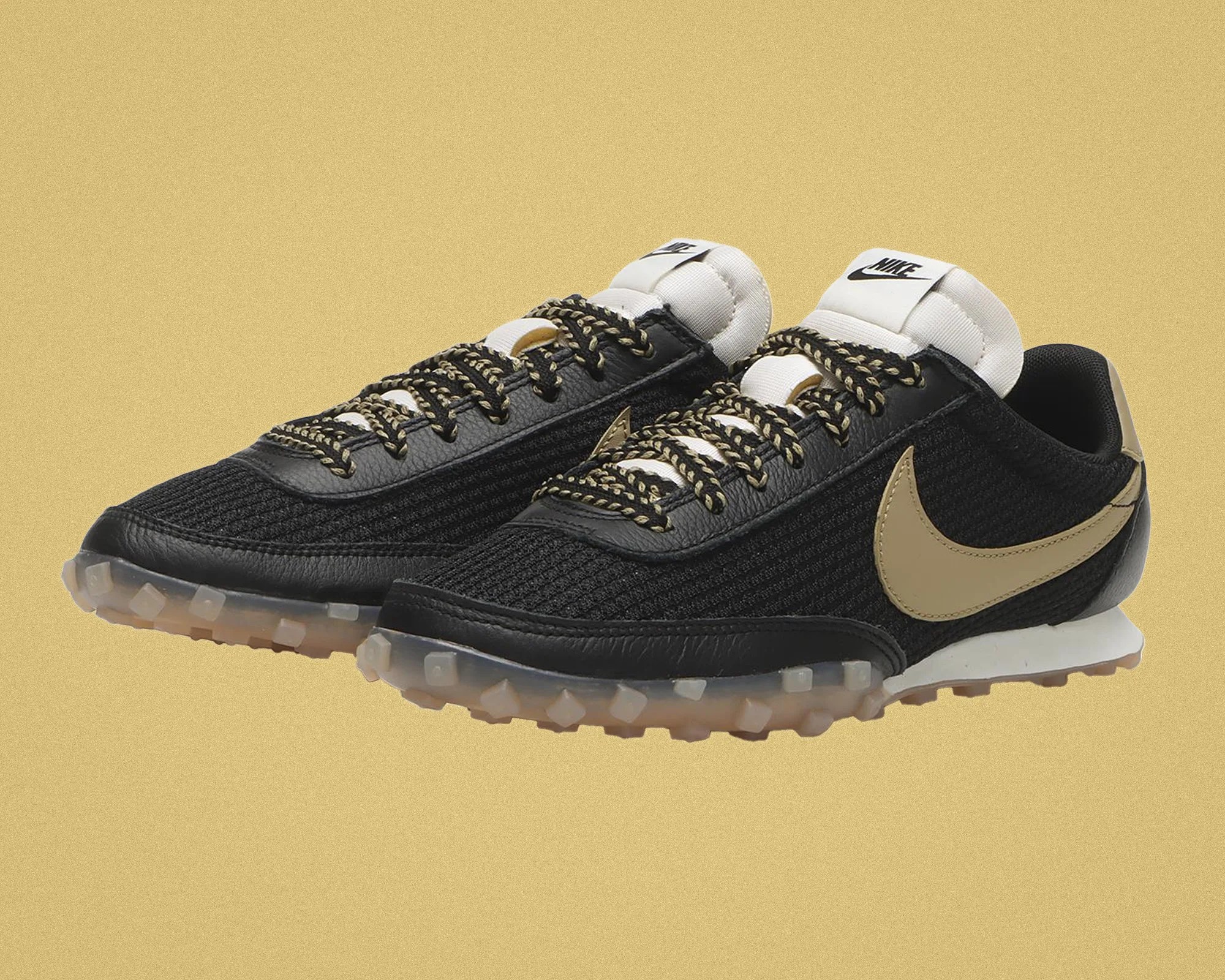 Pair of black Nike sneakers with beige swoosh, white padded tongue, and translucent rubber soles.