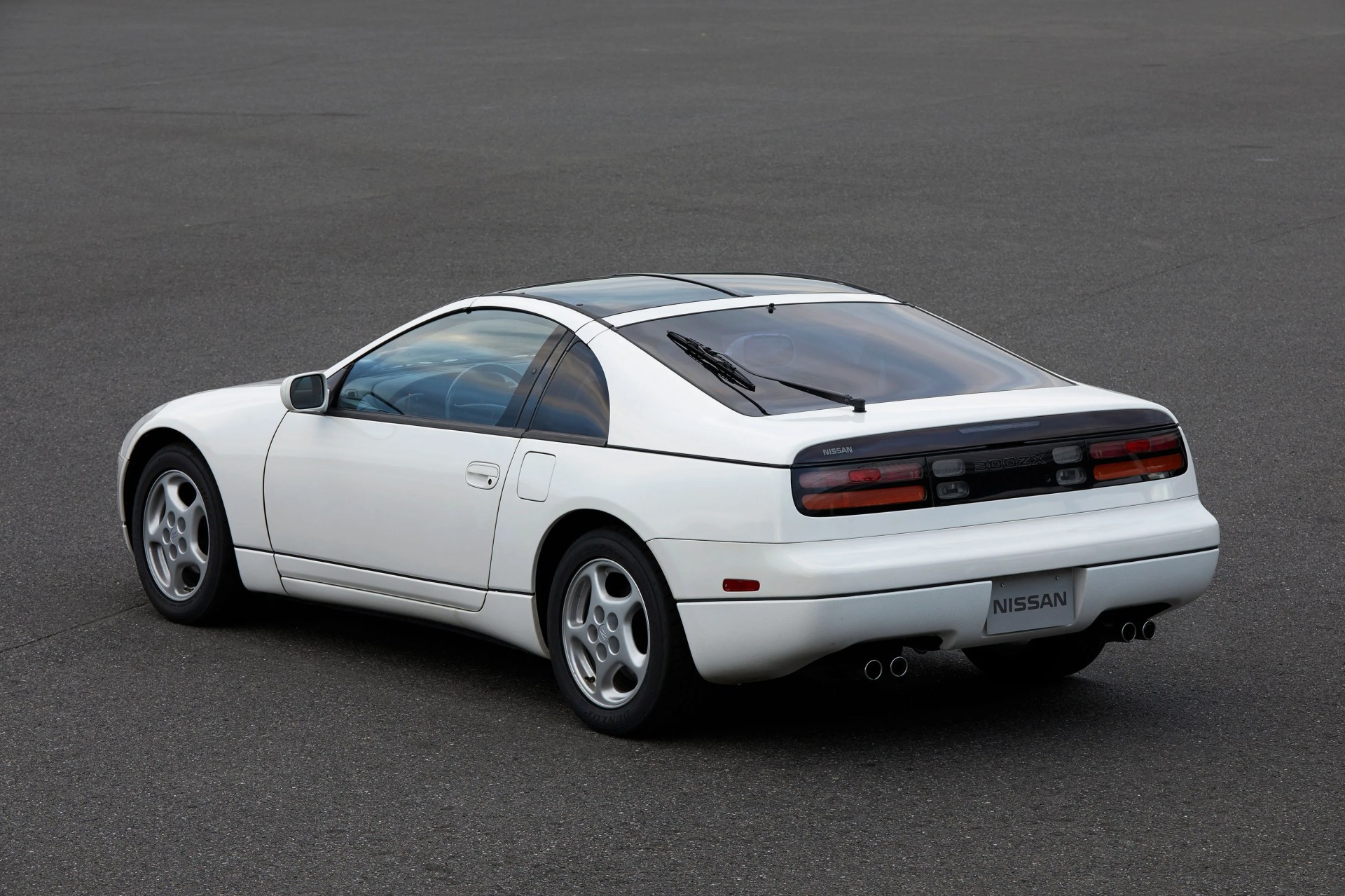 White Nissan 300ZX sports car rear three-quarter view on asphalt surface.