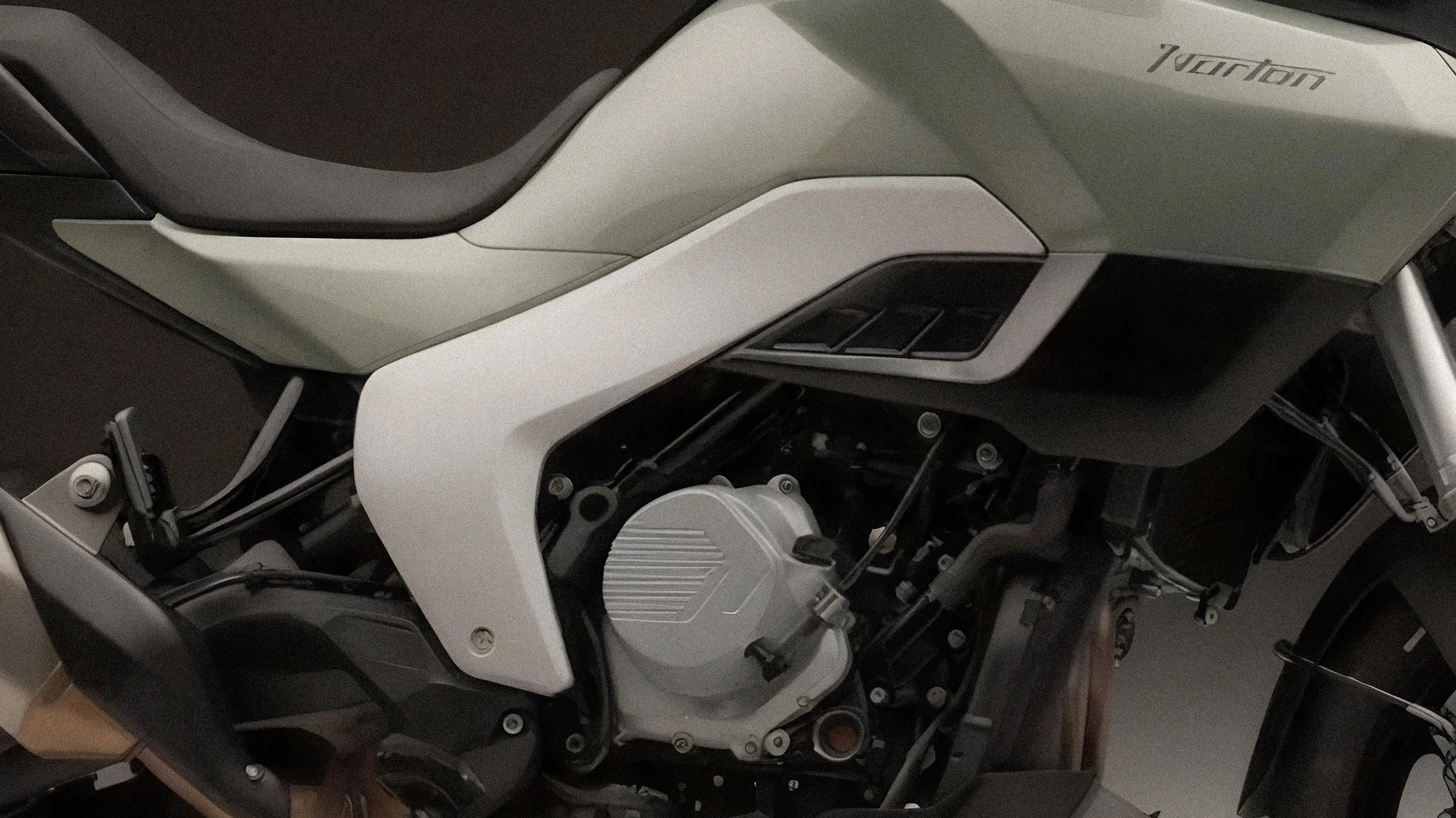 Close-up of a white and black Norton motorcycle engine and seat area.