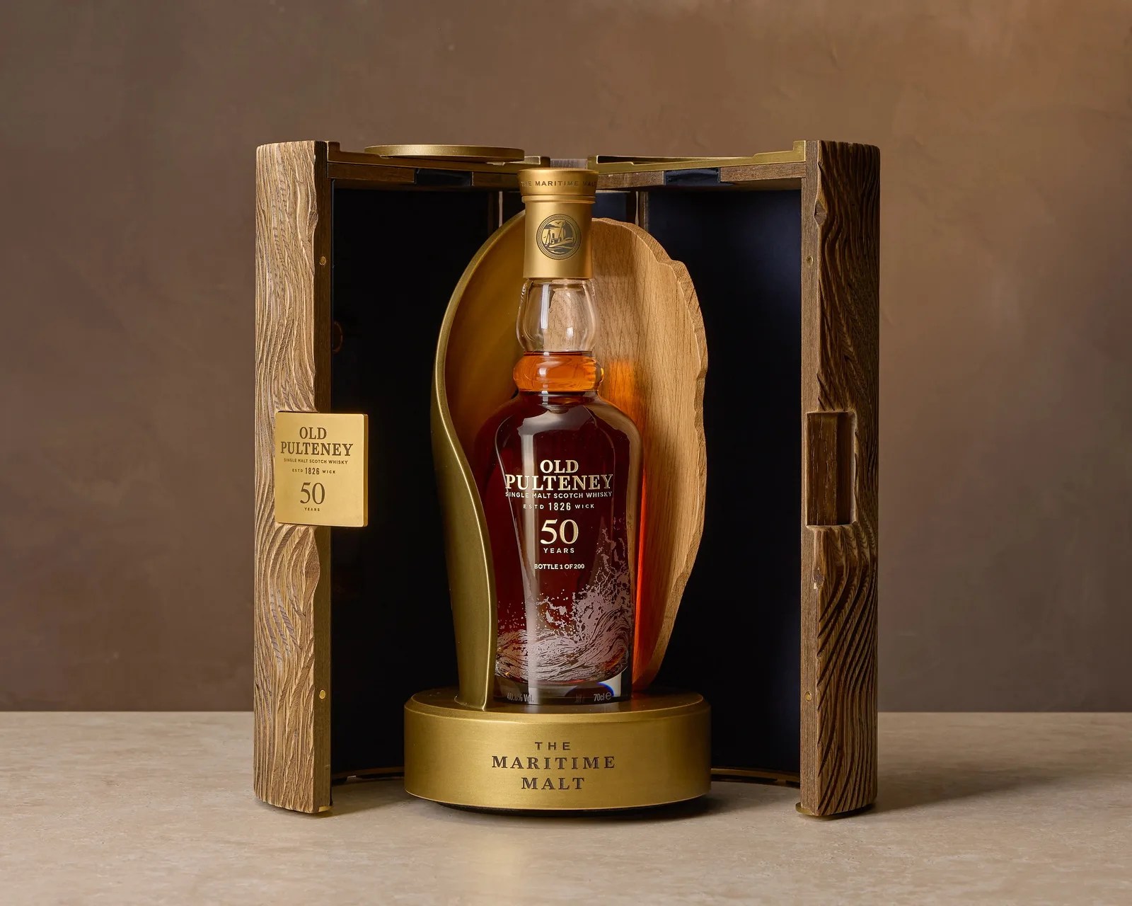 Bottle of Old Pulteney 50 Years single malt Scotch whisky in a wooden and gold display case.