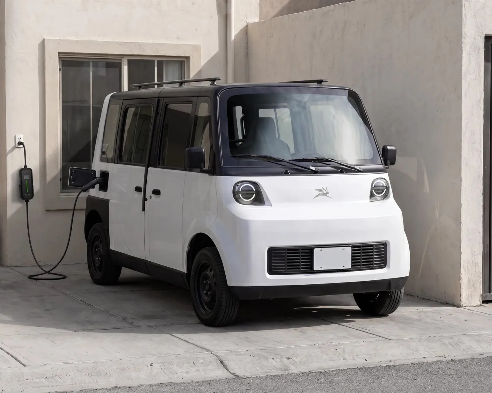 White and black compact electric car charging on a driveway next to a beige building.