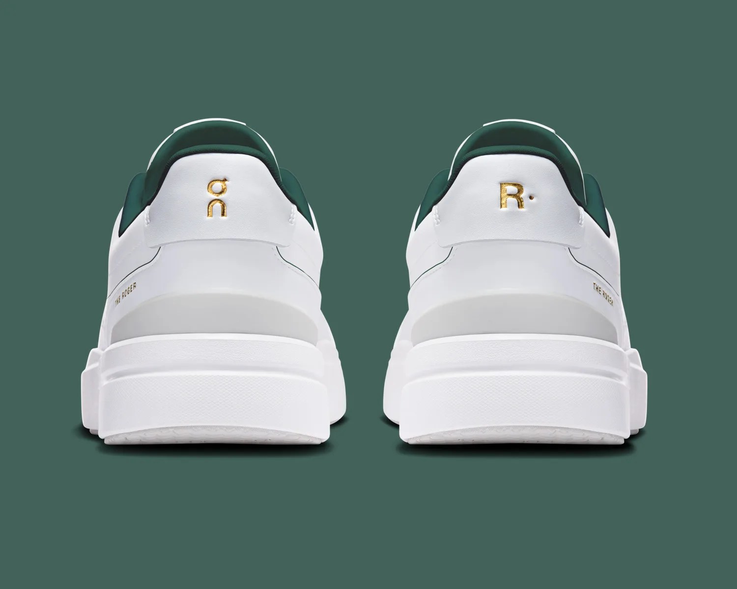 Pair of white sneakers with dark green inner lining and gold "on" and "R." logos on the heels.