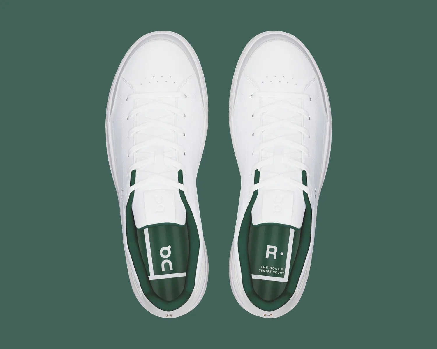Pair of white leather sneakers with white laces and dark green insoles featuring "on" and "R. The Roger Centre Court" text.