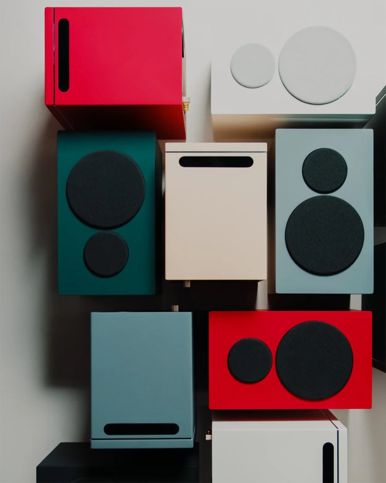 Colorful rectangular speakers with circular black speaker covers arranged in a grid on a wall.