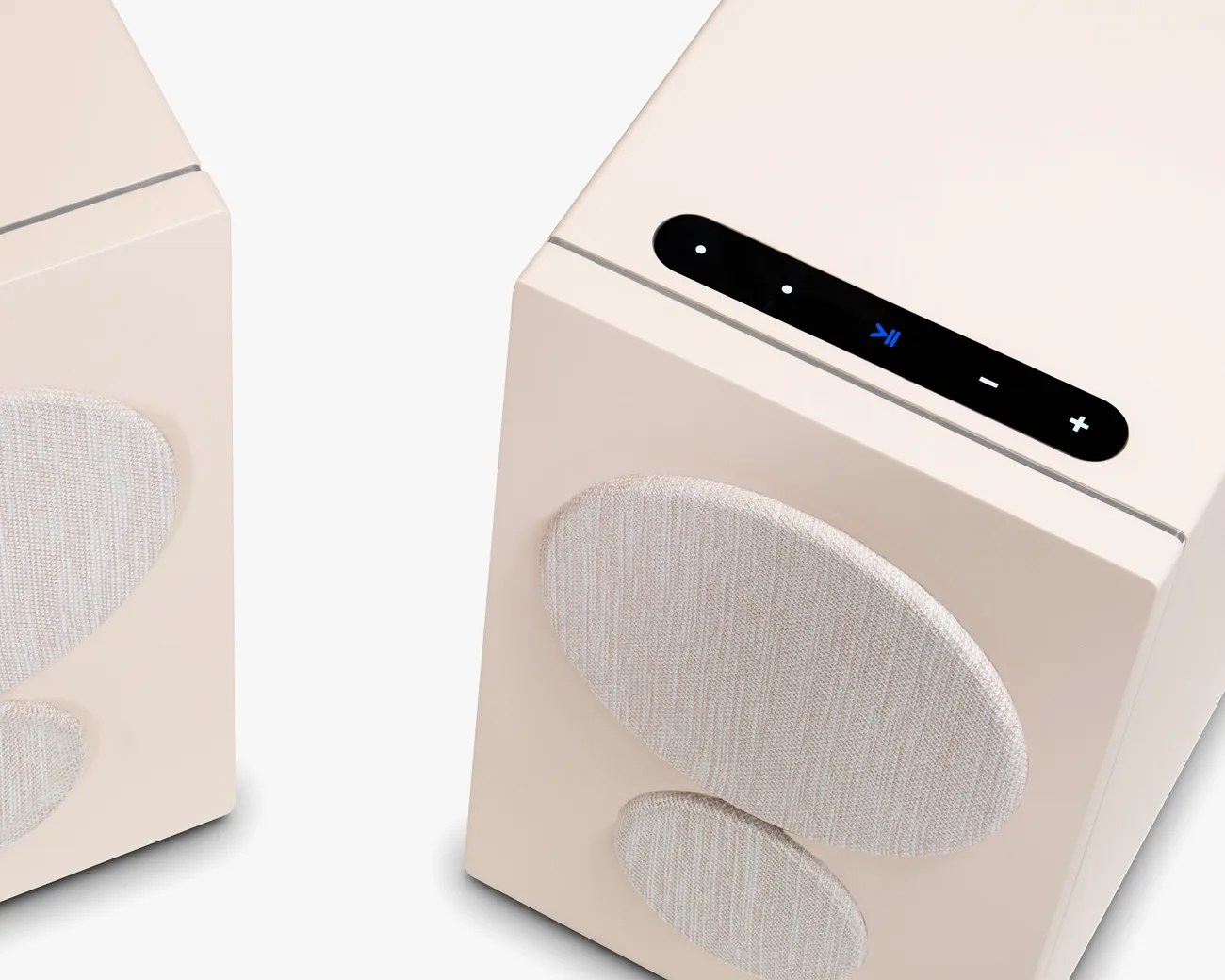 Two beige cube-shaped speakers with fabric-covered circular drivers and a black control panel on top.