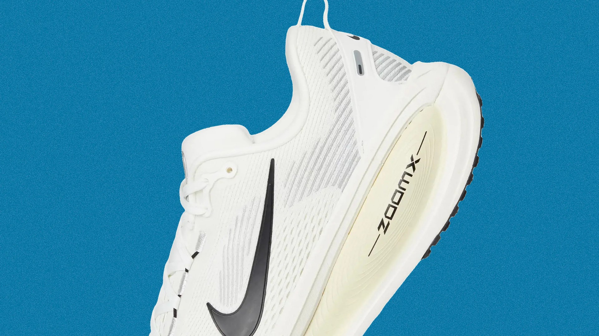 White Nike ZoomX running shoe with black swoosh logo and cream-colored sole against blue background.