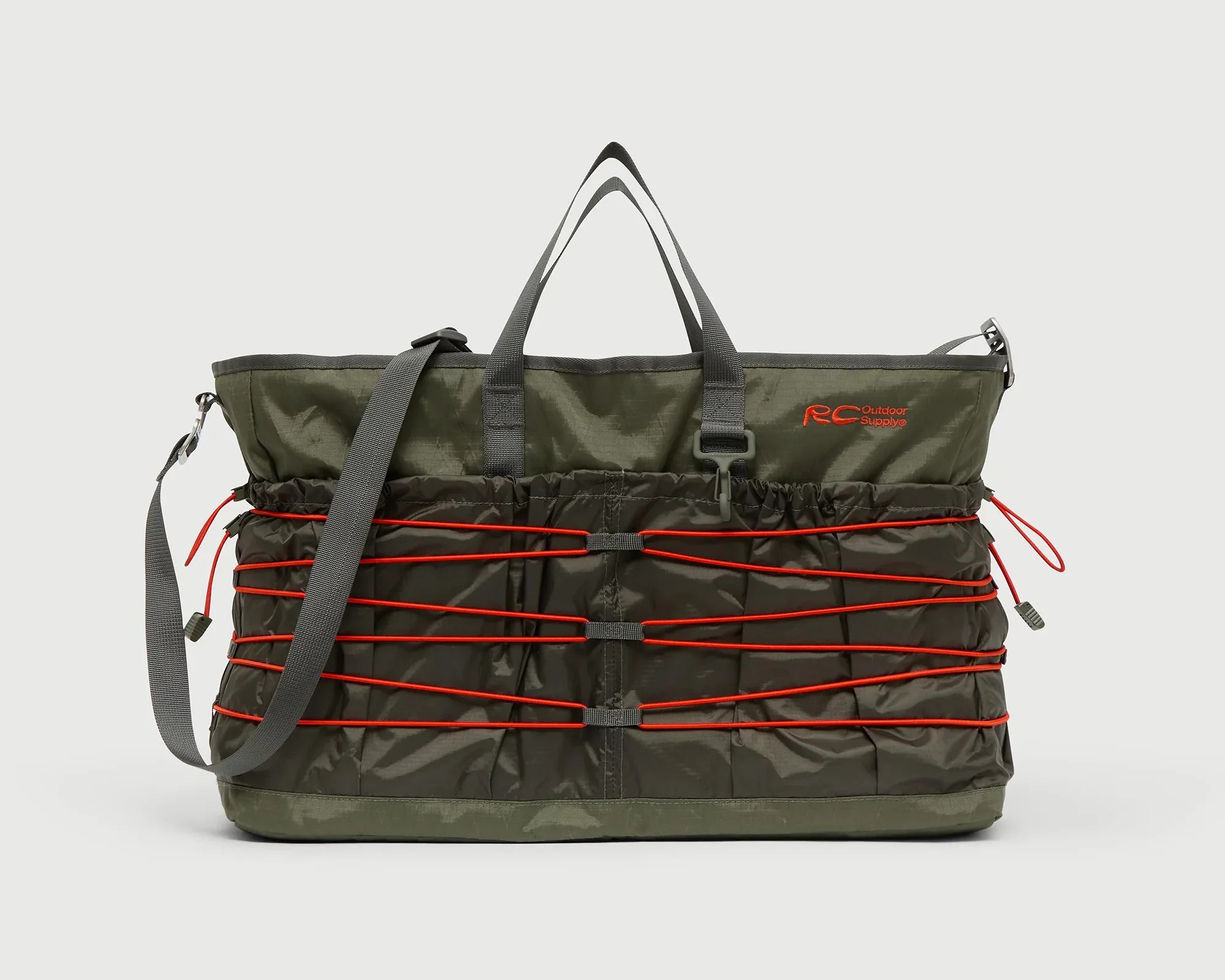 Olive green RC Outdoor Supply tote bag with red bungee cords and gray straps.