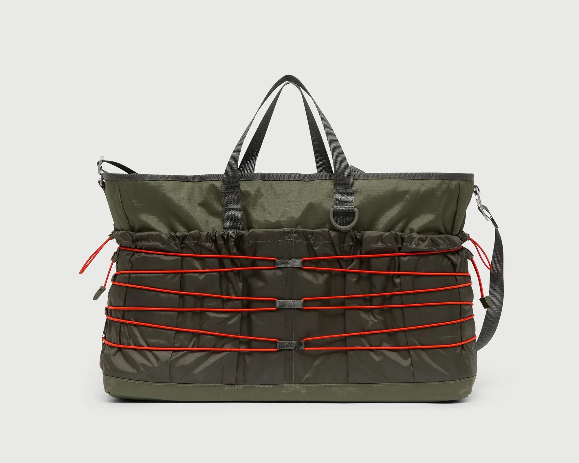 Olive green and dark green tote bag with black handles and red elastic cords across the front.