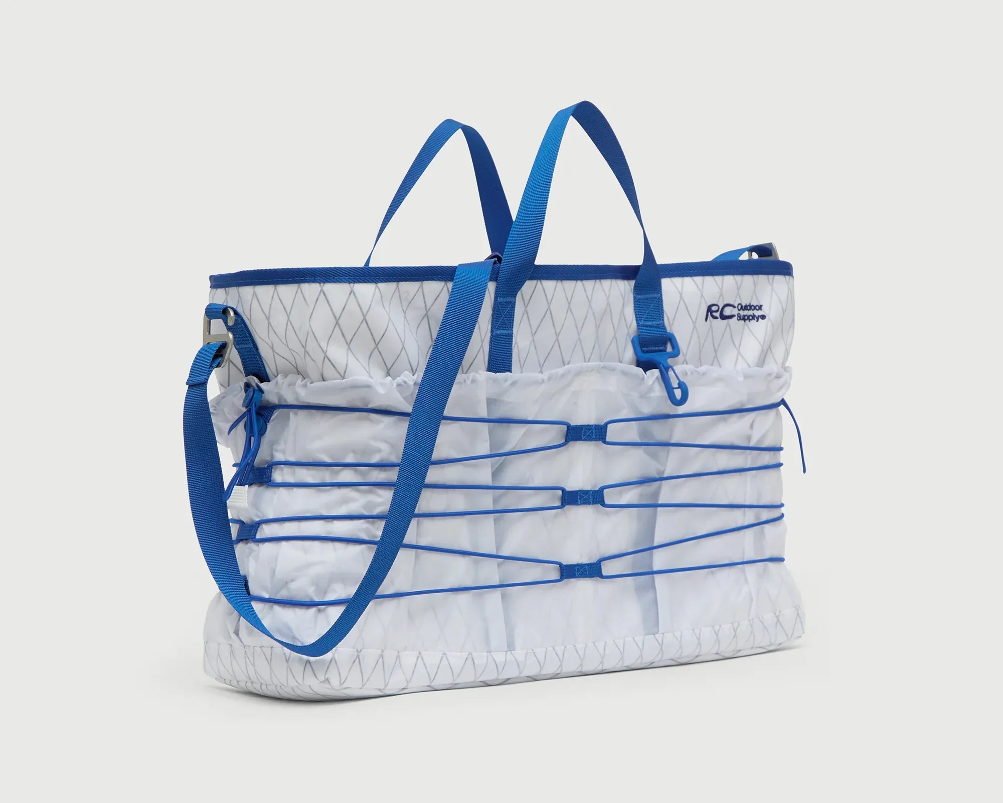 White and blue RC Outdoor Supply tote bag with blue straps and bungee cords on the front.
