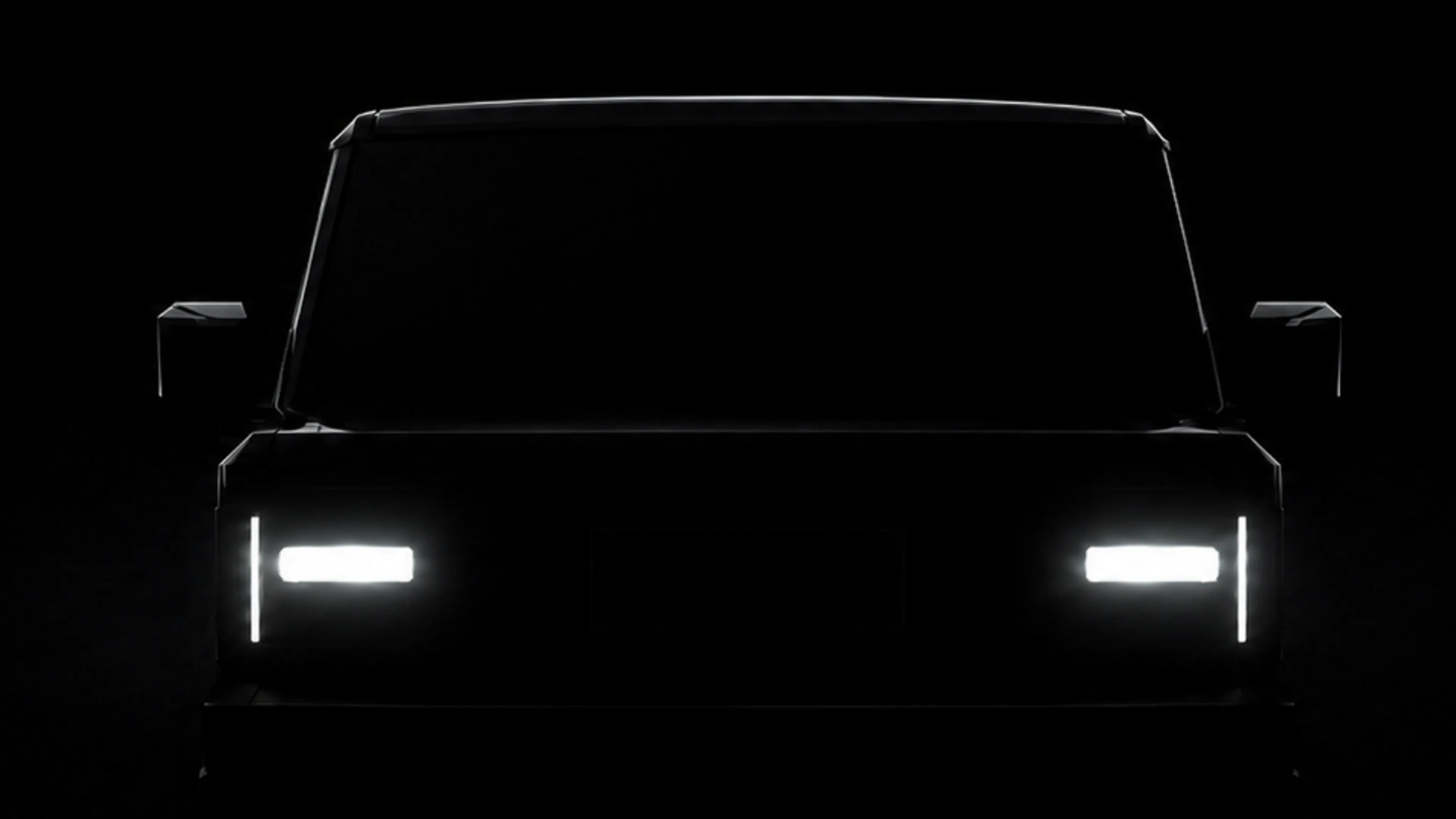 Front view of a vehicle with illuminated rectangular headlights and vertical LED daytime running lights in a dark setting.