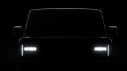 Front view of a vehicle with illuminated rectangular headlights and vertical LED daytime running lights in a dark setting.