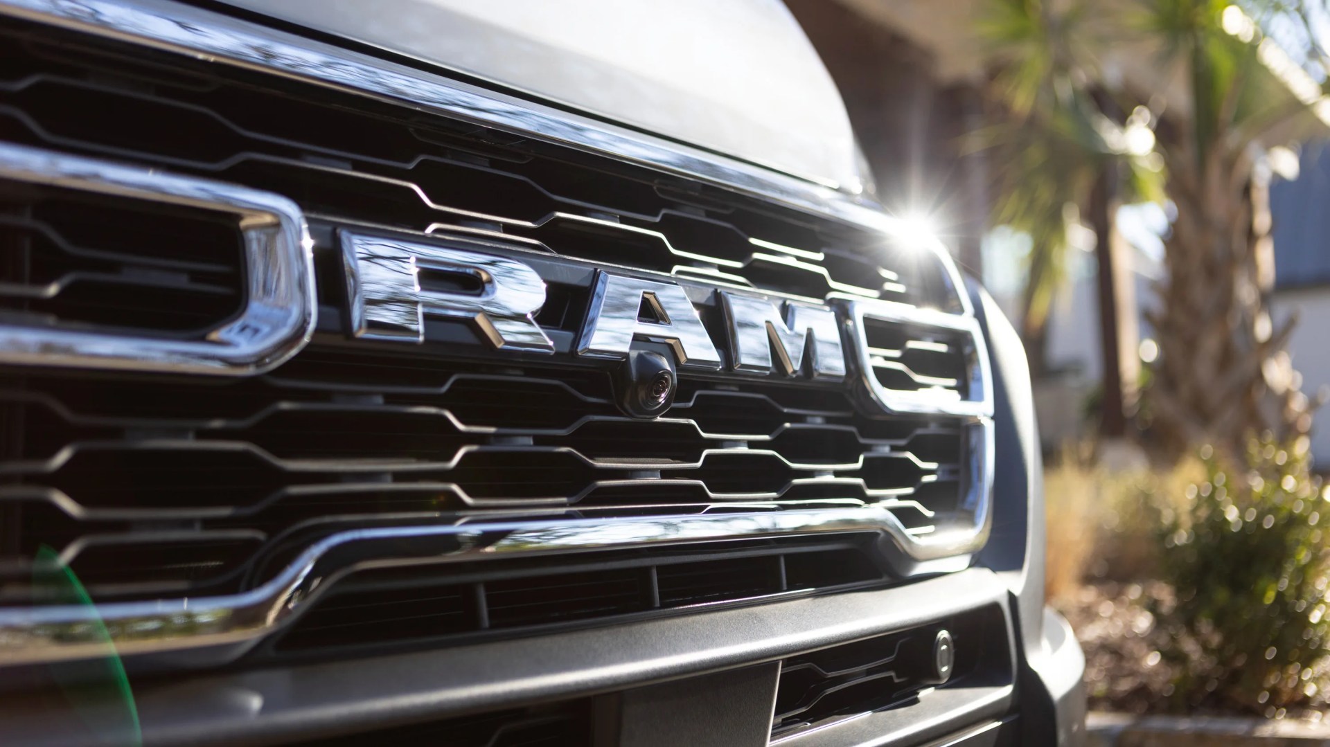 Close-up of a black RAM truck grille with chrome letters and a front camera.