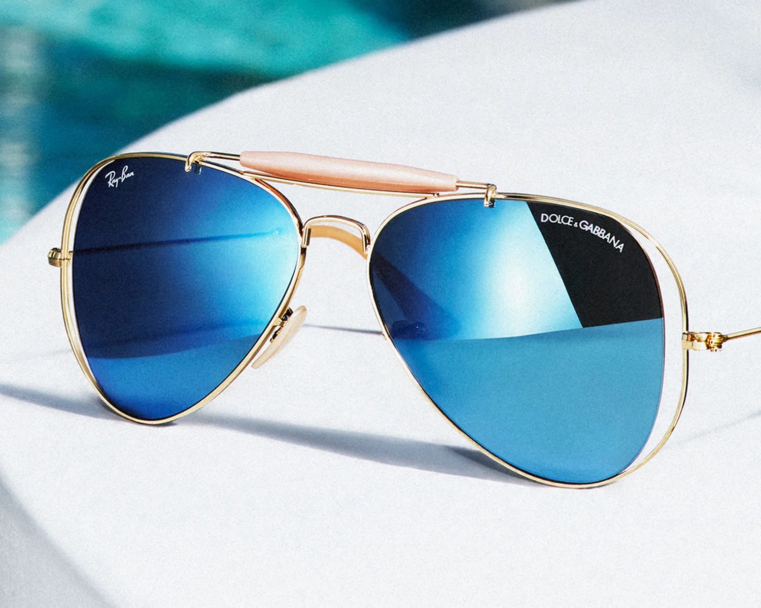 Aviator sunglasses with gold frames and blue gradient lenses, branded Ray-Ban and Dolce & Gabbana.