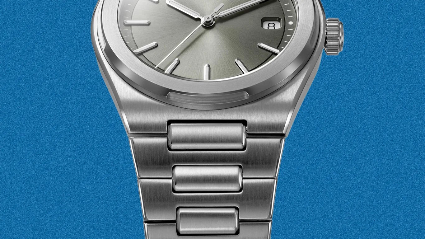 Close-up of a silver stainless steel watch with a brushed metal bracelet and a gray dial showing the date "8".