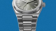 Close-up of a silver stainless steel watch with a brushed metal bracelet and a gray dial showing the date "8".