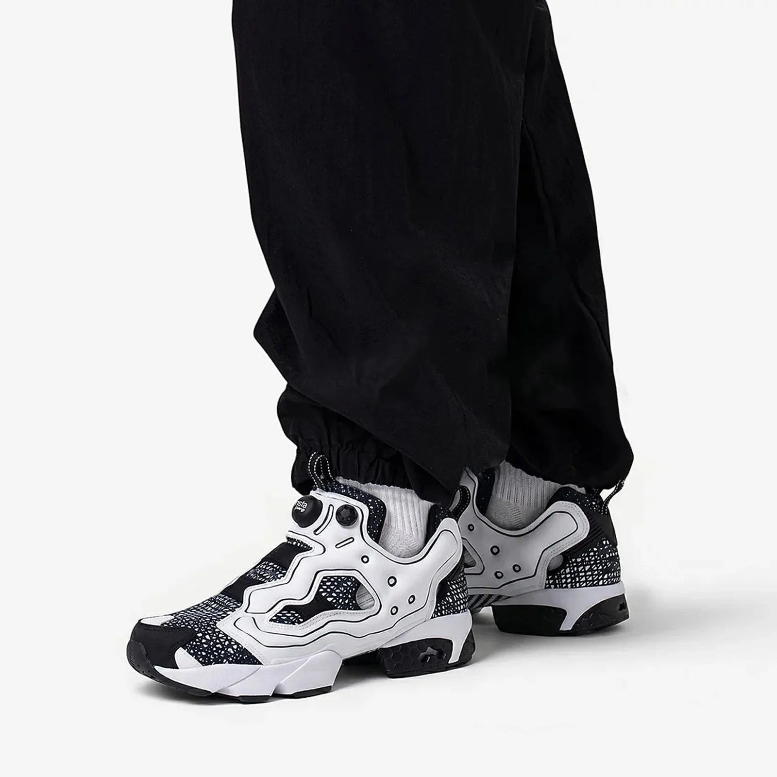Black and white patterned sneakers worn with black pants and white socks.