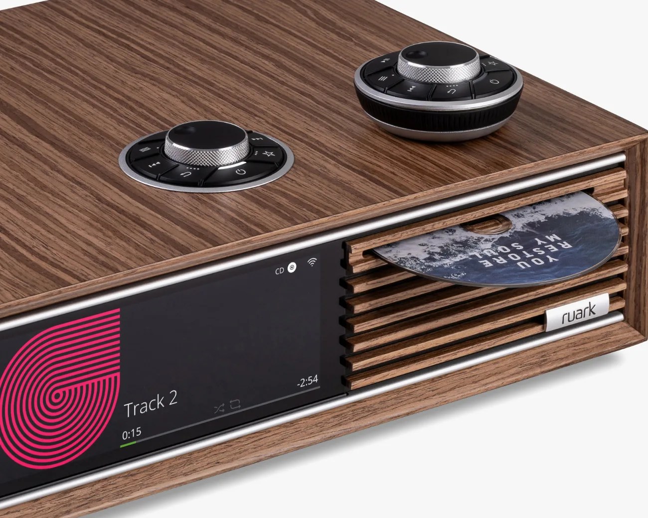 Wood-finished Ruark audio system with CD slot, digital display showing Track 2, and two circular control knobs on top.