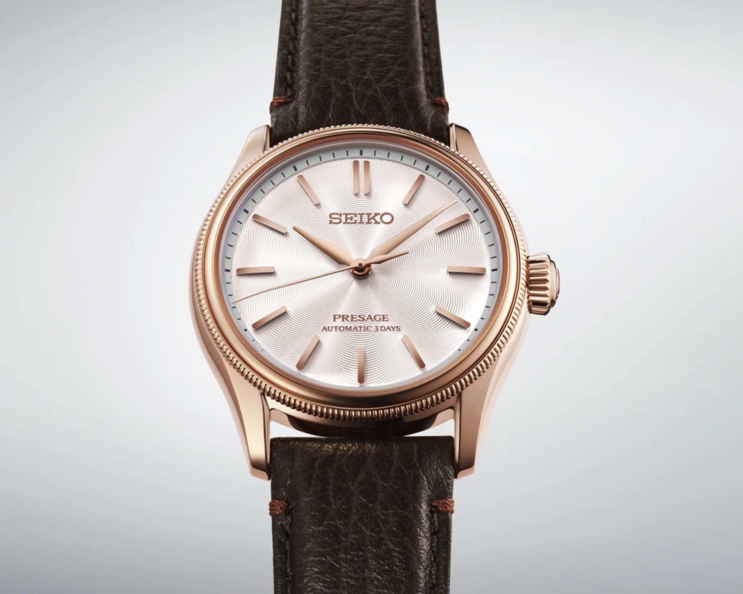 Rose gold Seiko Presage automatic watch with textured white dial and dark brown leather strap.