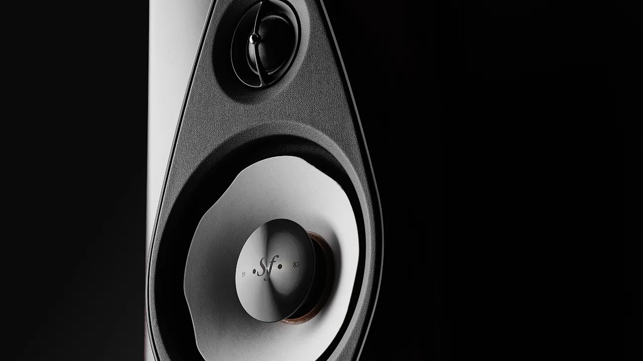 Close-up of a black and white speaker cone with "sf" and "1983" printed on the dust cap against a dark background.