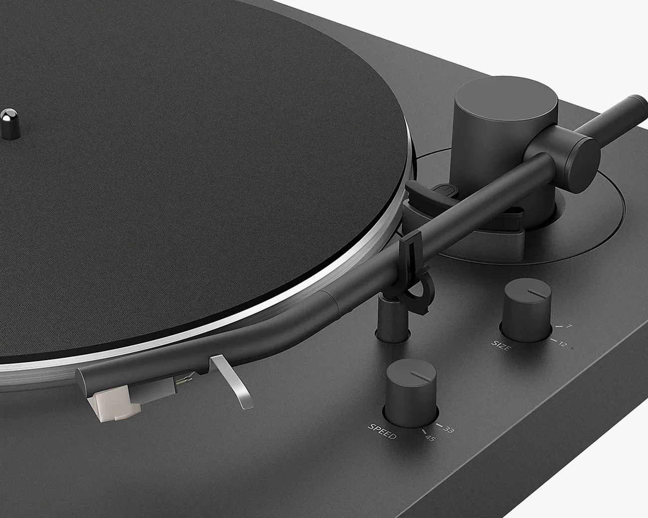 Close-up of a matte black turntable tonearm with speed and size control knobs on a dark gray base.