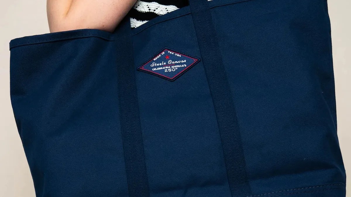 Navy blue canvas tote bag with black handles and a diamond-shaped Steele Canvas logo patch.