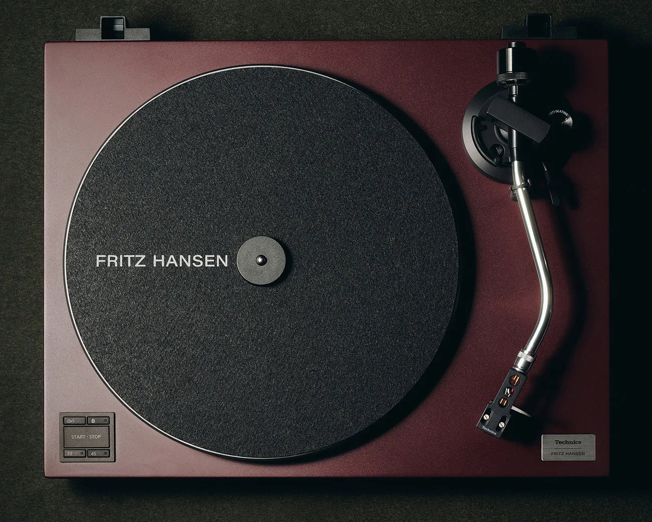 Maroon Technics turntable with black felt platter mat labeled "Fritz Hansen" and silver tonearm.