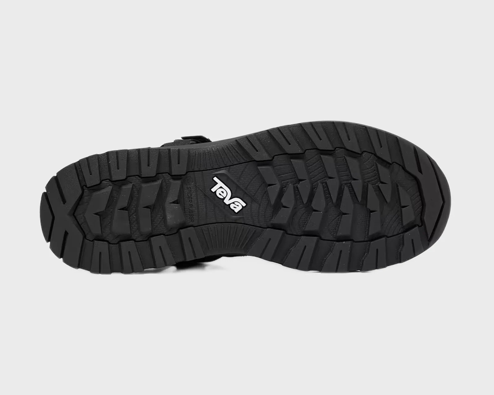 Black rubber outsole with deep treads and white Teva logo in the center.