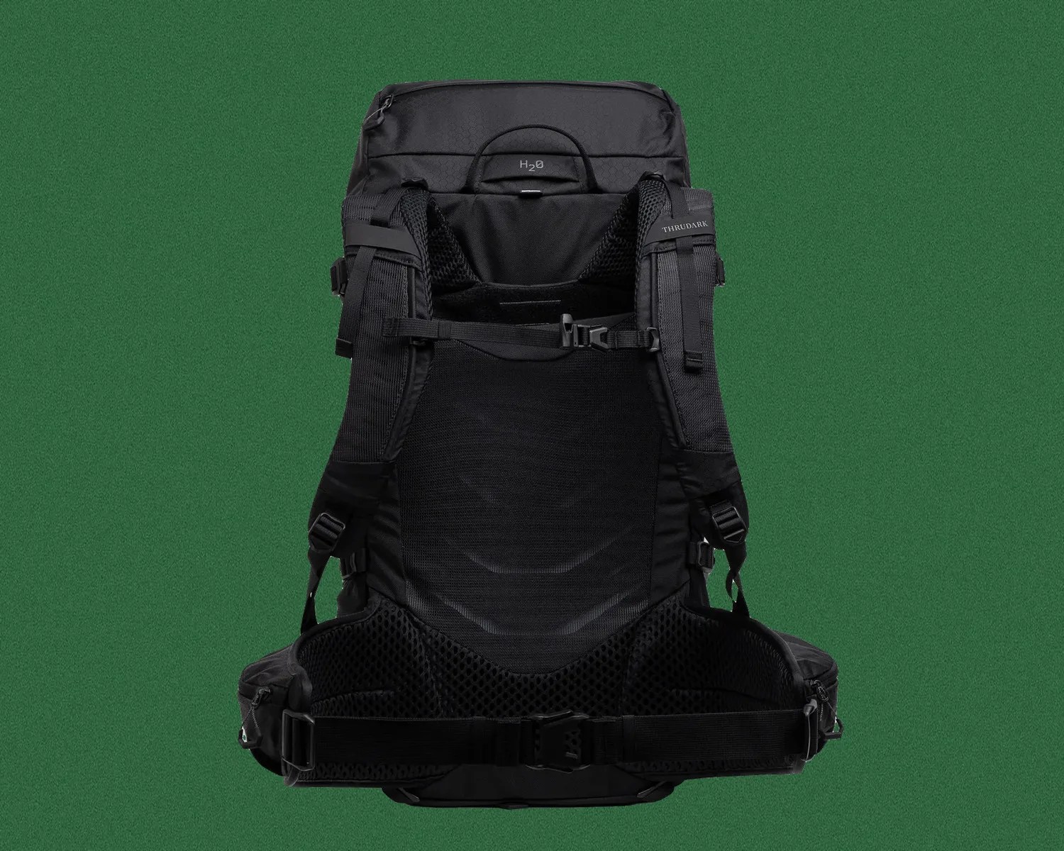 Black tactical backpack with padded shoulder straps, mesh back panel, and adjustable waist belt on green background.