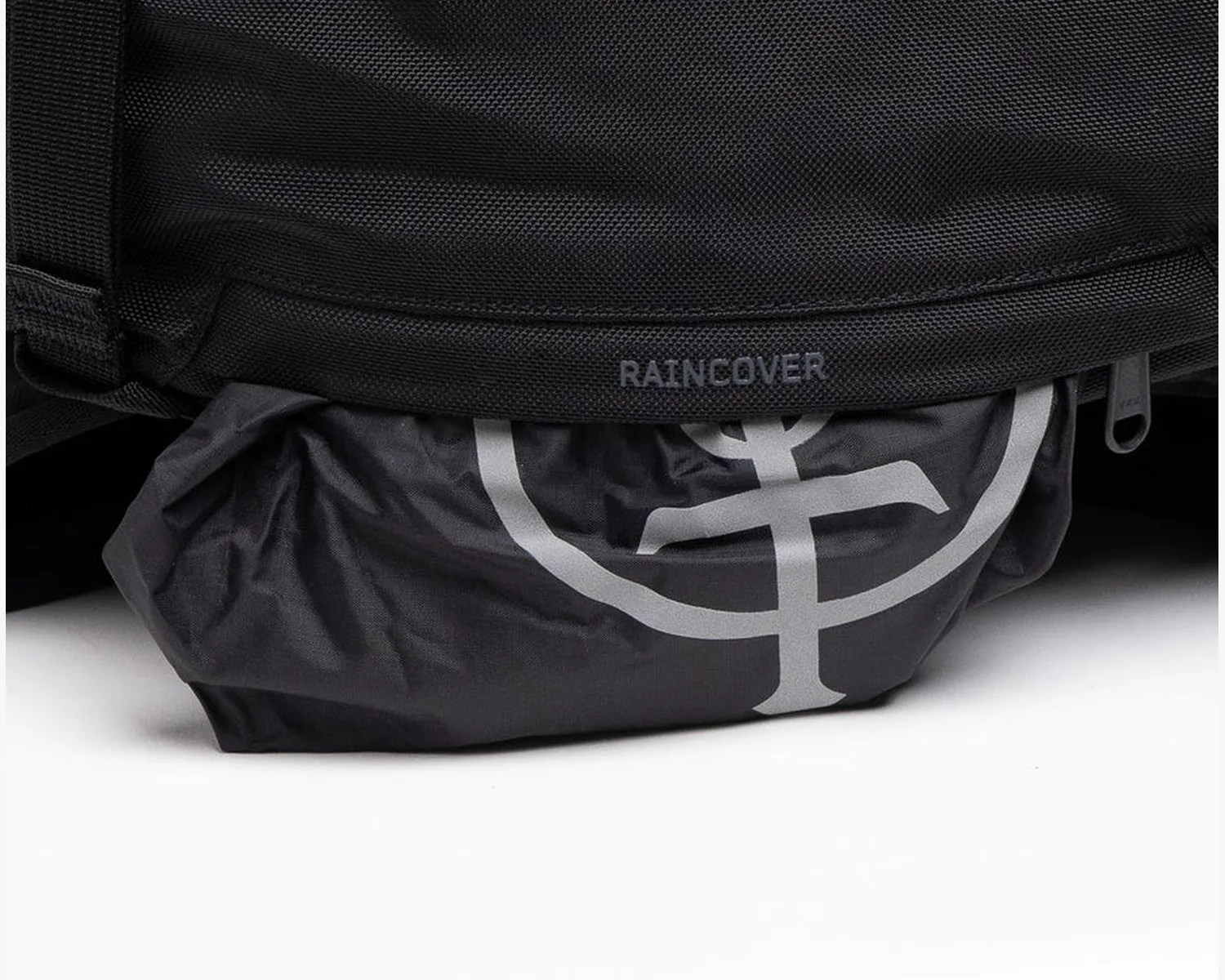 Black fabric raincover partially tucked under a black textured bag with "RAINCOVER" text.