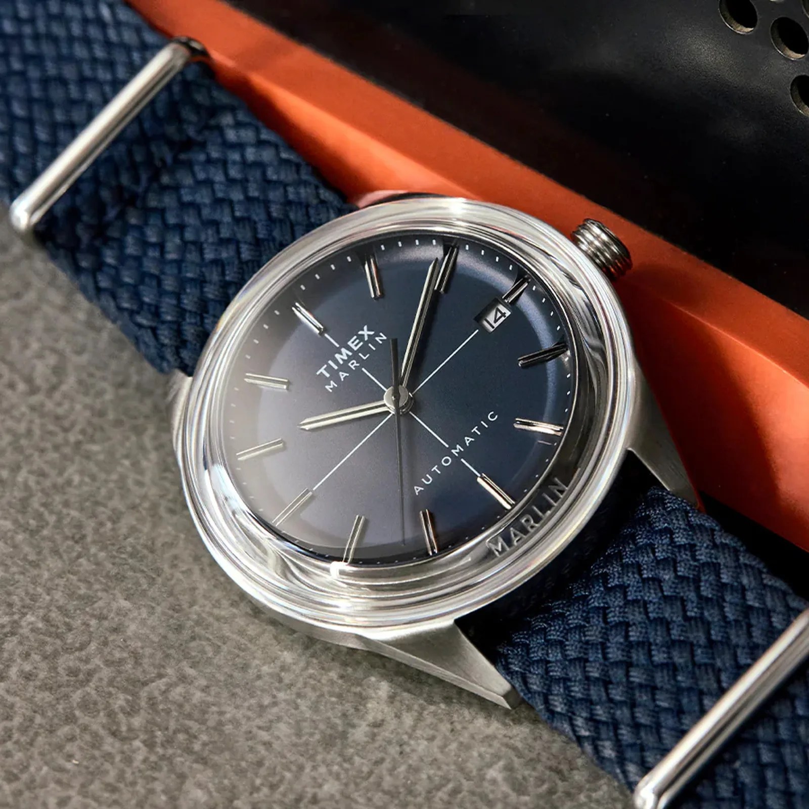 Close-up of a Timex Marlin automatic watch with a blue dial and woven navy strap.