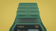 Green Timex T80 digital watch with segmented strap on a yellow background.