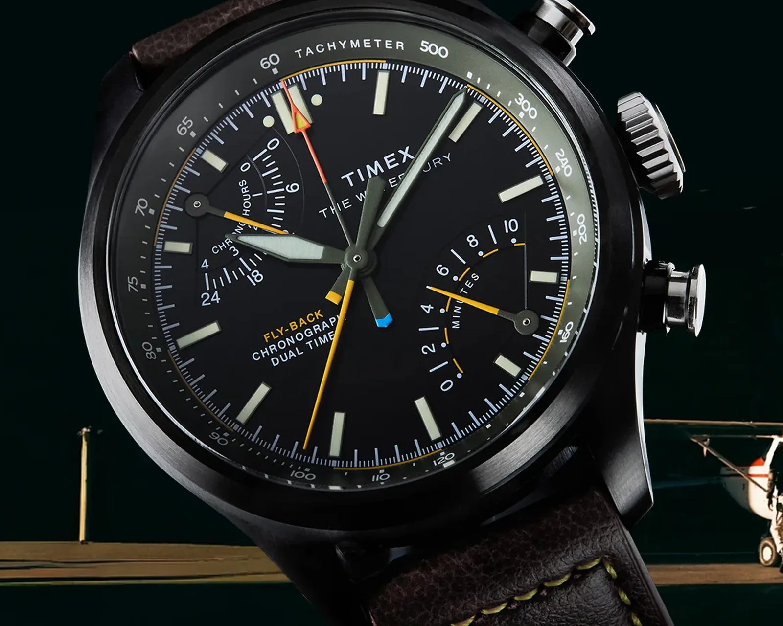 Close-up of a black Timex chronograph watch with tachymeter, dual time, and fly-back features on a brown leather strap.