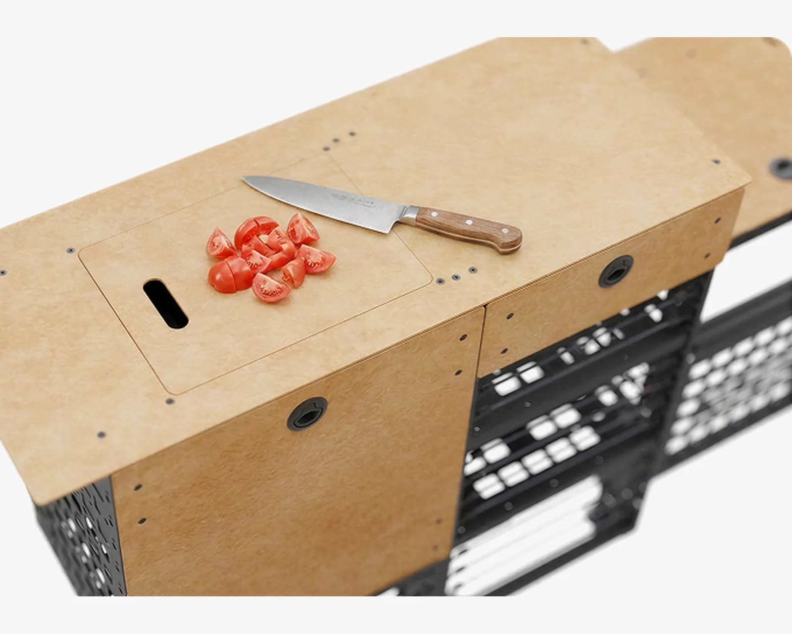 Wooden cutting board with a chef's knife and chopped tomatoes on top of a black crate structure.