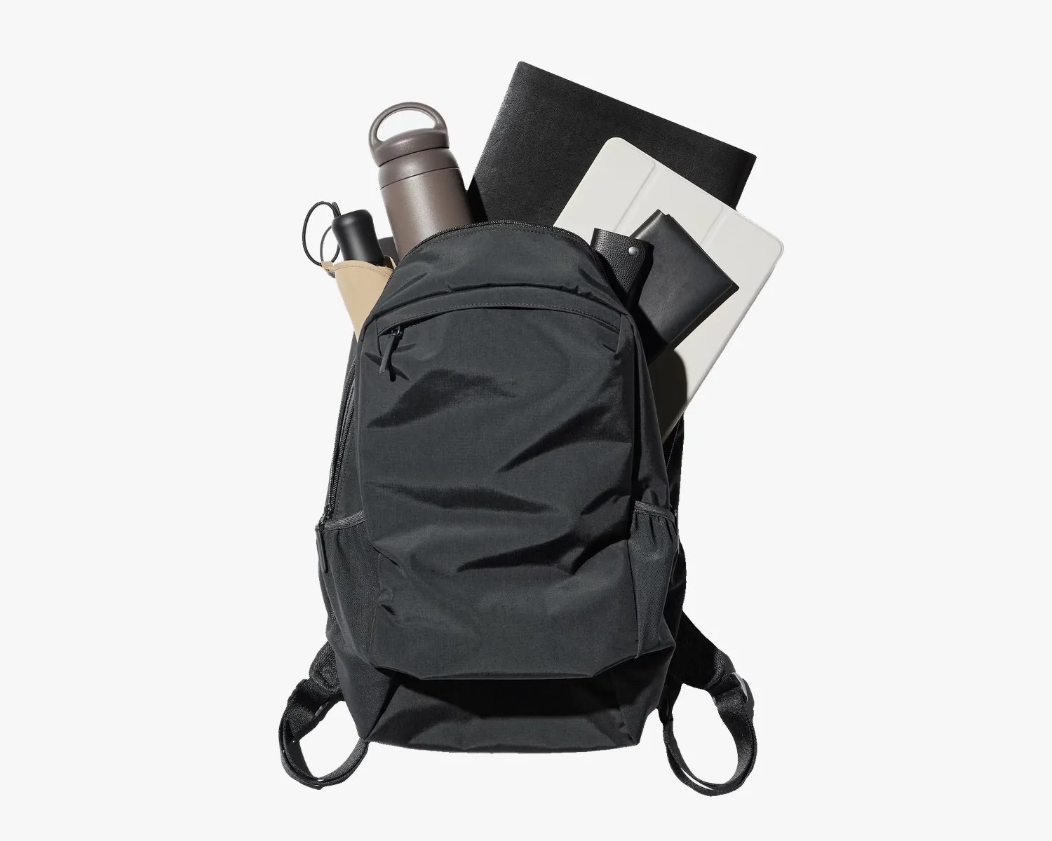 Black backpack filled with a gray water bottle, black notebook, white tablet, and black wallet.