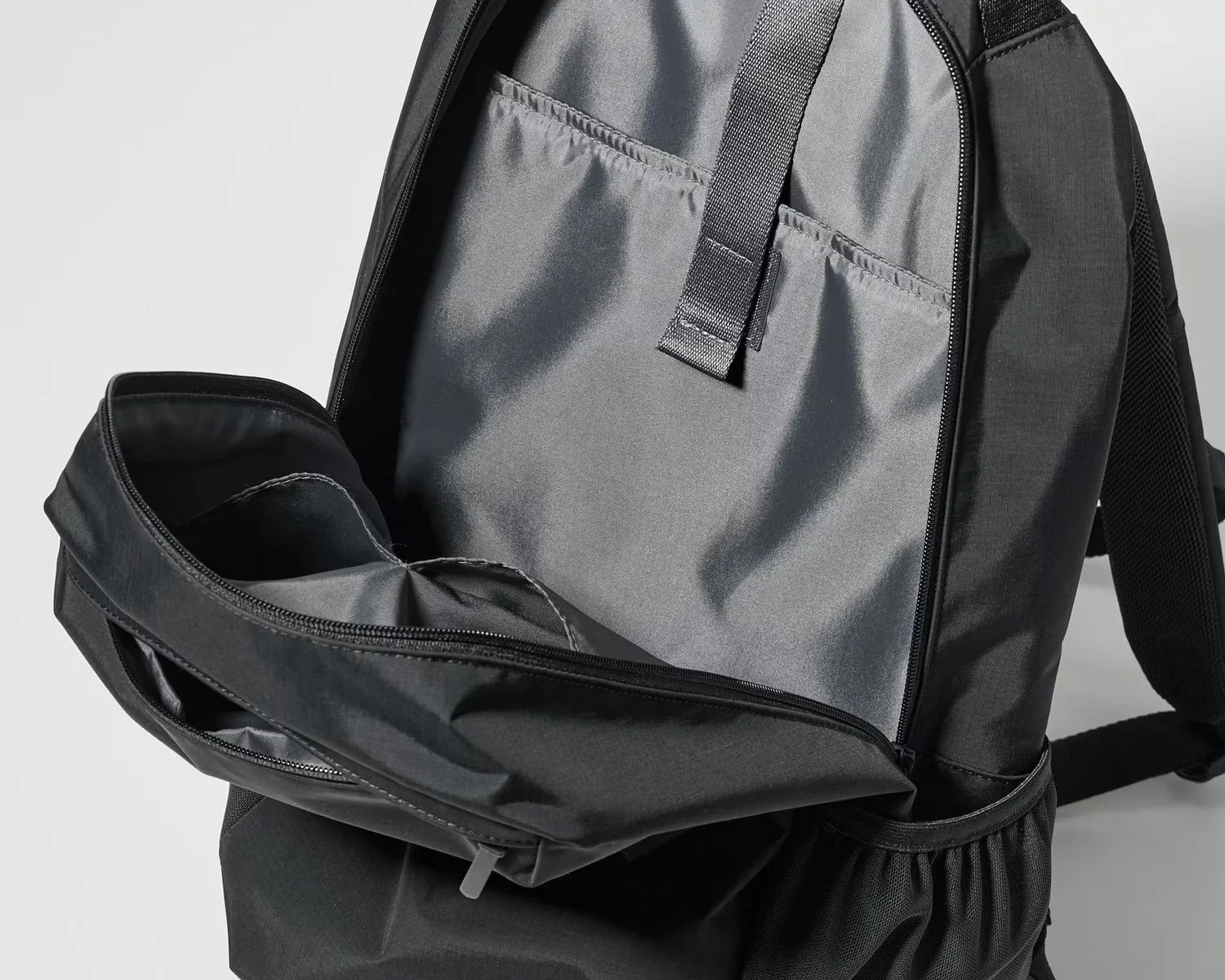 Black backpack with open main compartment showing padded laptop sleeve and internal strap.