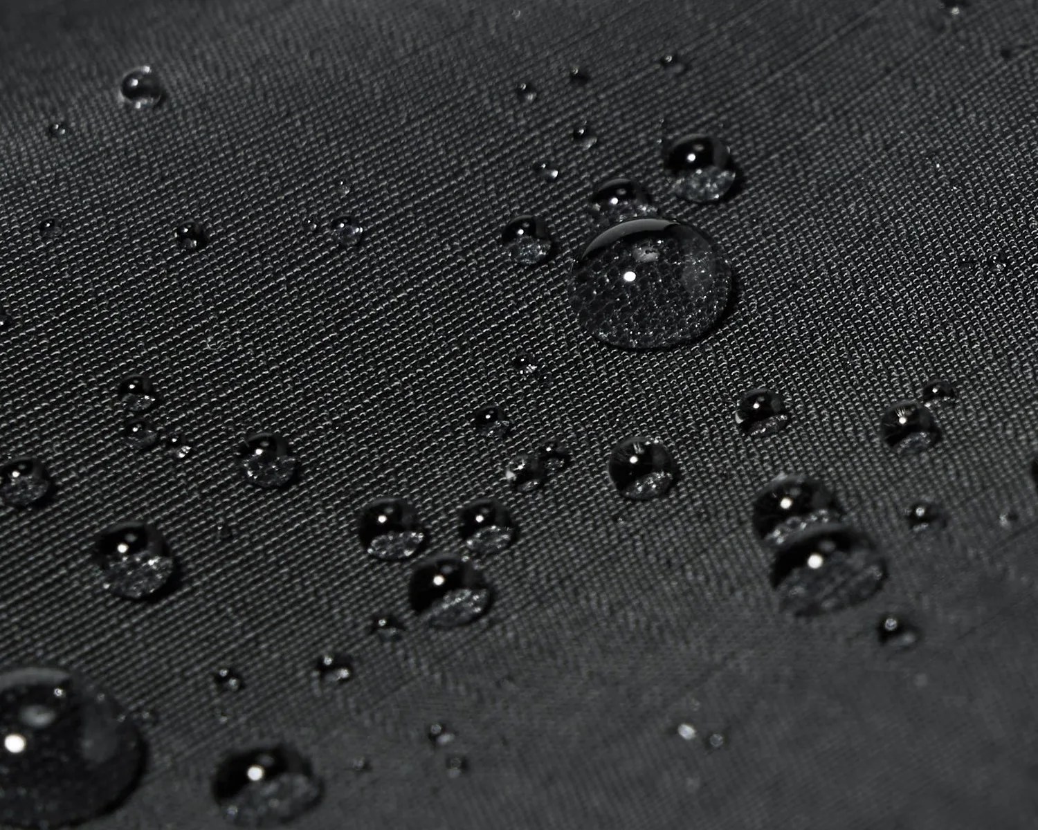 Water droplets beading on black textured waterproof fabric.