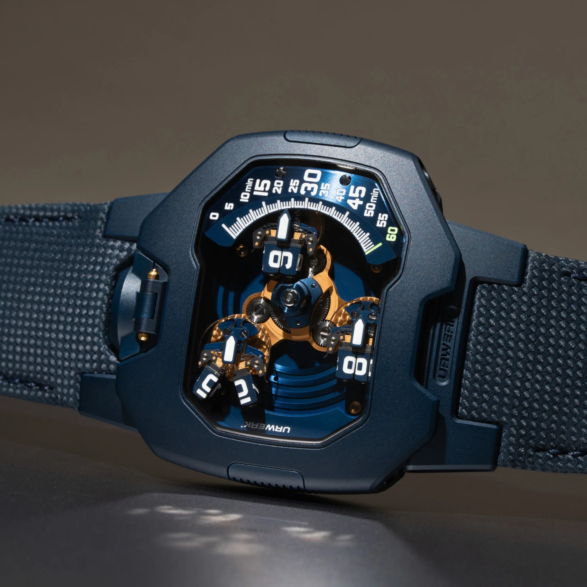 Close-up of a blue mechanical wristwatch with visible gears and a unique numeric time display on a textured blue strap.