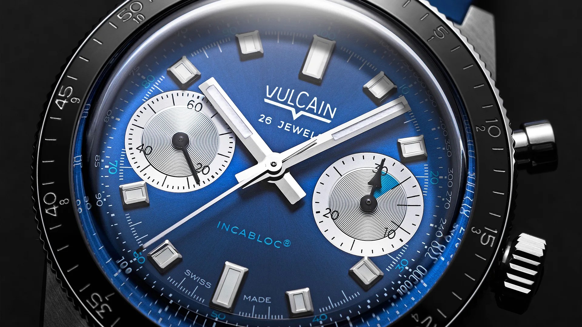 Close-up of a Vulcain wristwatch with a blue dial, silver rectangular hour markers, two white subdials, and a black bezel with minute markings.