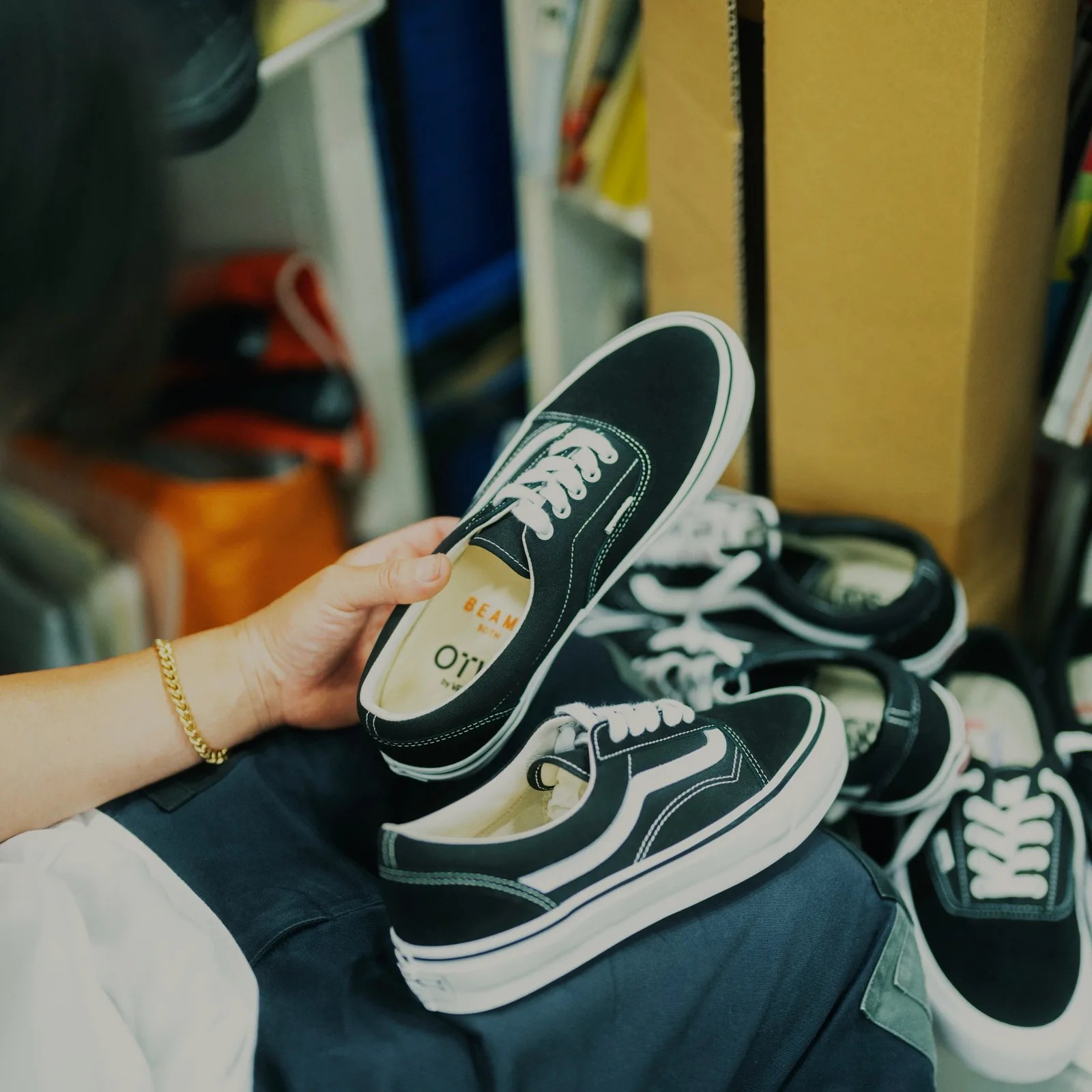 Hand holding a black and white canvas sneaker with white laces and a white sole.