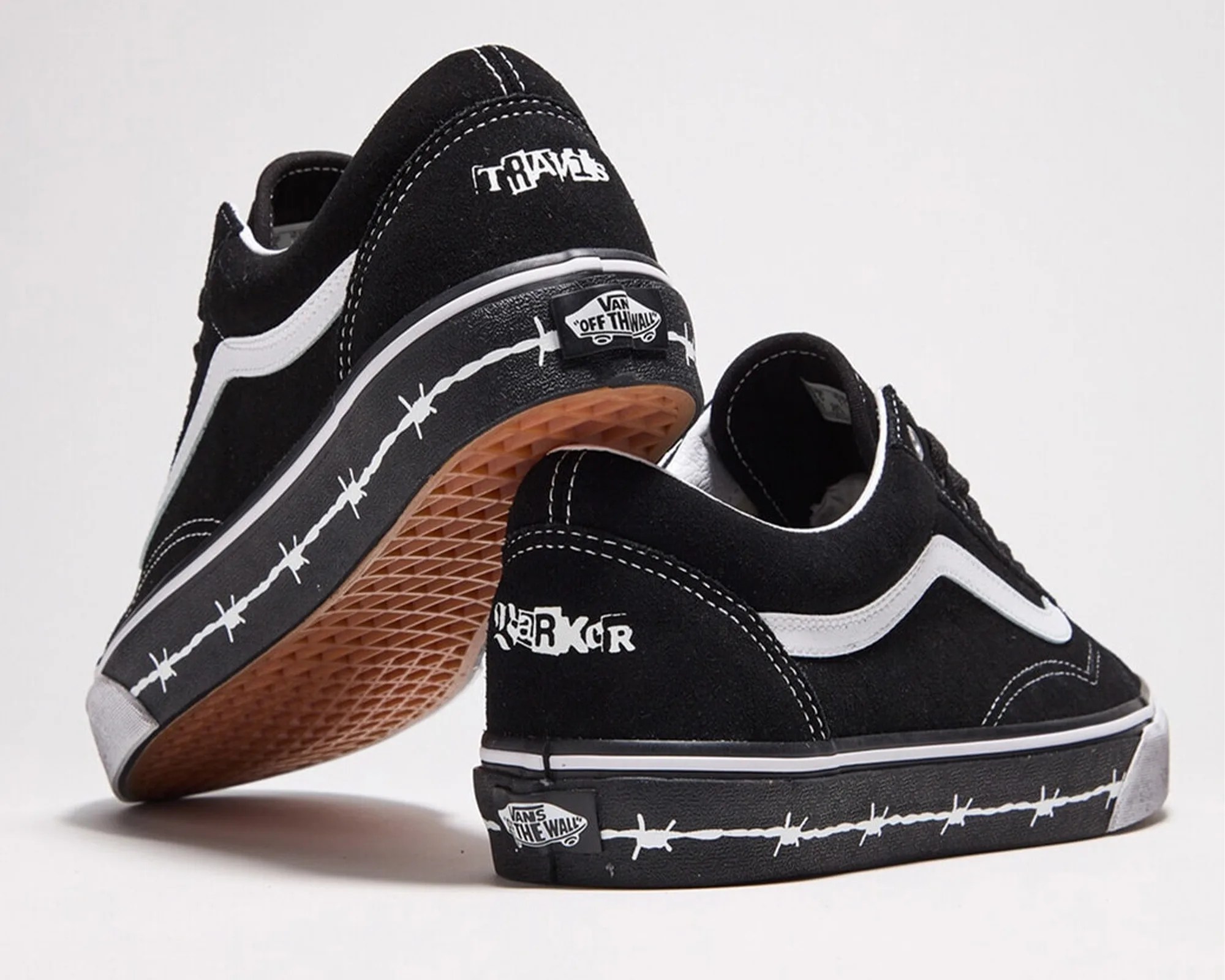 Pair of black Vans sneakers with white side stripes, barbed wire design on the sole, and "TRAVIS" and "RANGER" text on the heel.