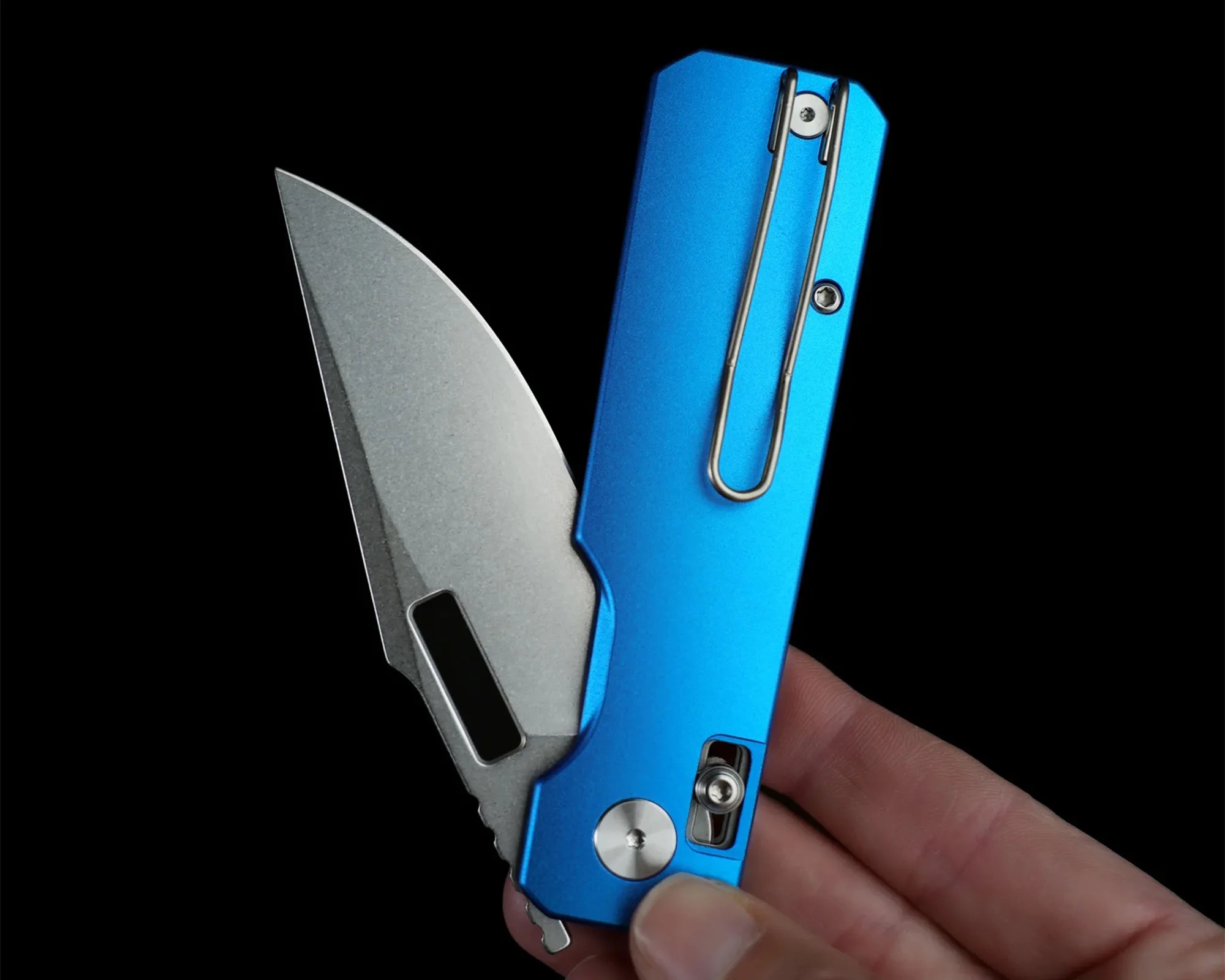 Blue metal folding knife with a partially open silver blade held in a hand against a black background.