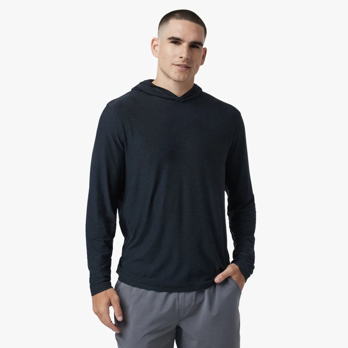 Man wearing a black long-sleeve hooded shirt and gray pants against a white background.
