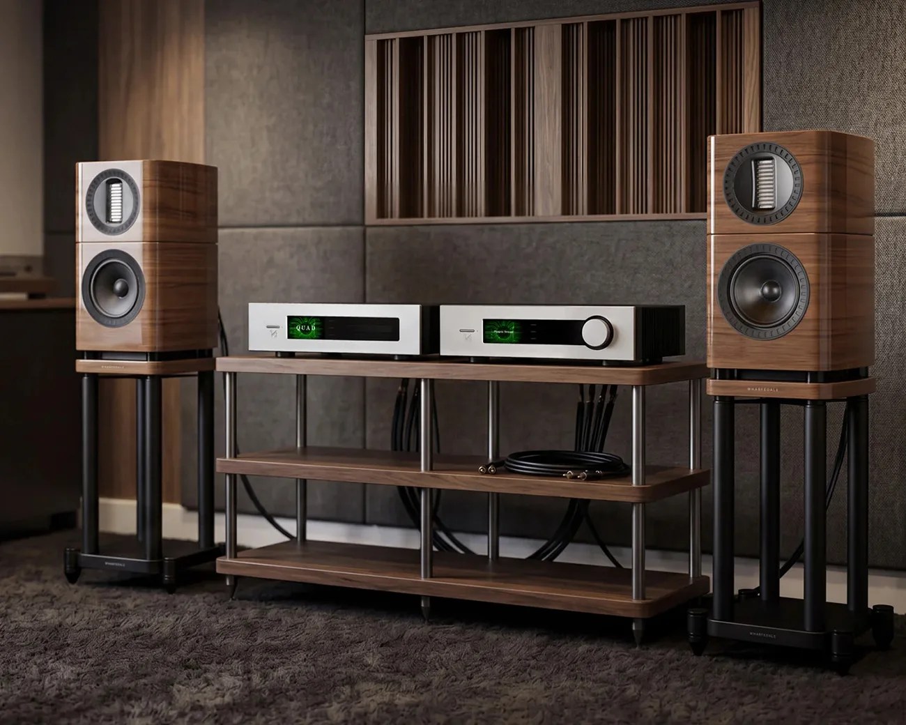 Pair of wooden bookshelf speakers on black stands flanking a wooden audio rack with silver stereo components.