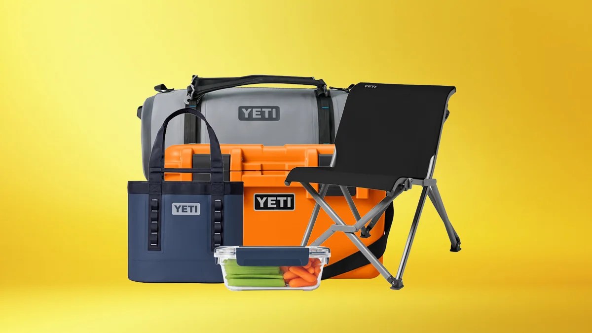 Collection of YETI outdoor gear including a gray duffel bag, orange cooler, navy tote, black folding chair, and clear container with vegetables.