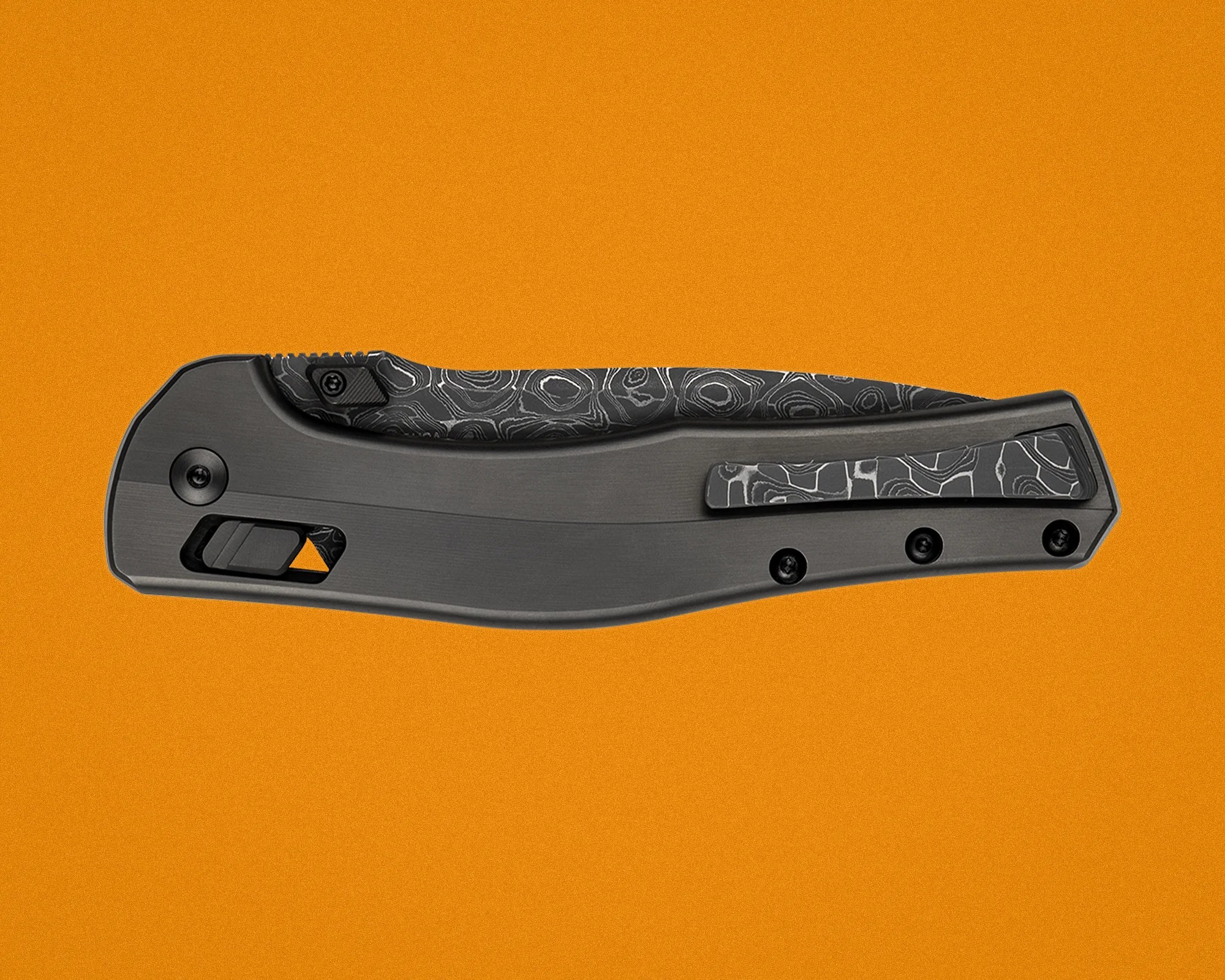 Black and gray folding knife handle with patterned clip and thumb stud on an orange background.