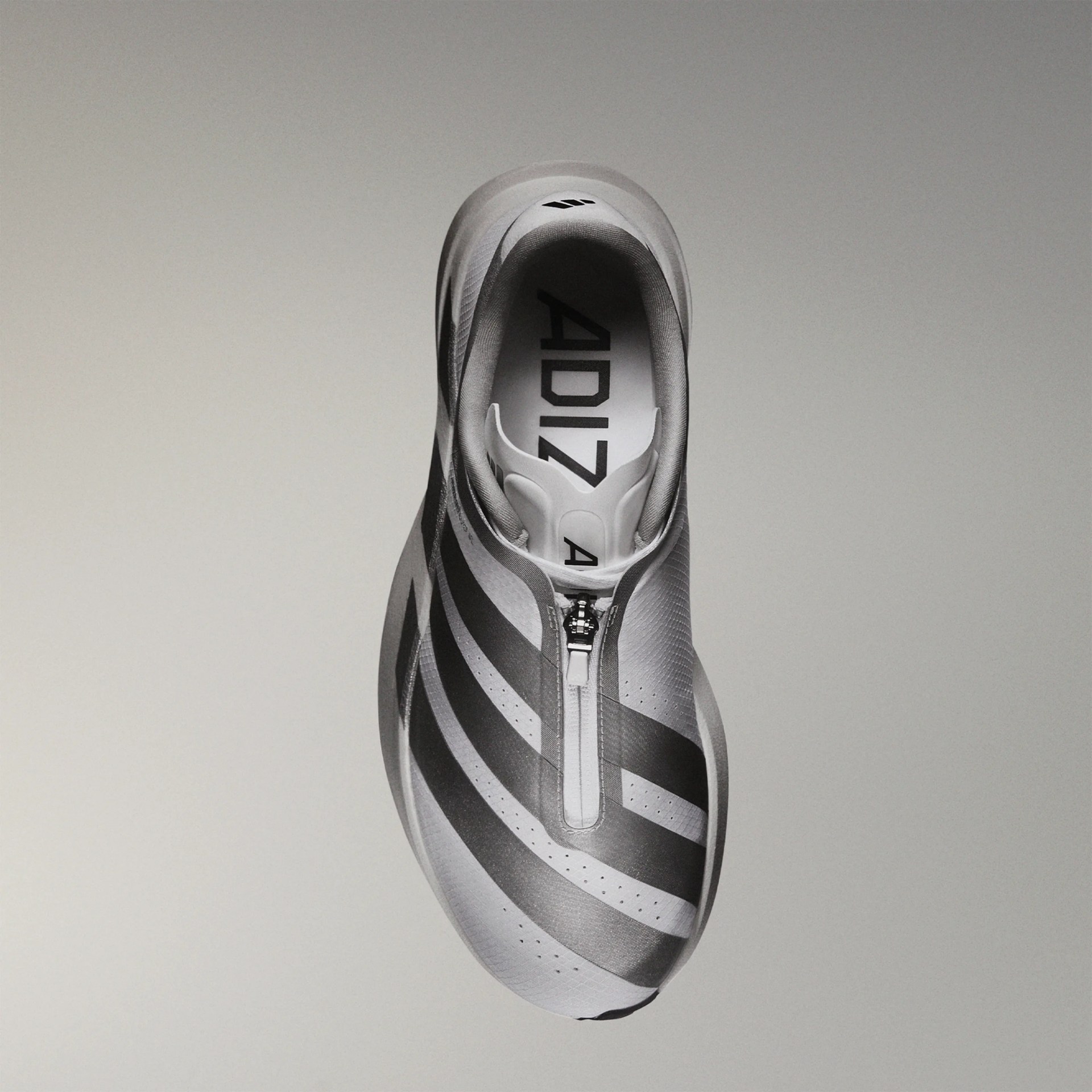 Top view of a gray Adidas running shoe with black stripes and a front zipper closure.